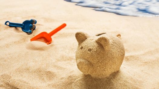 Piggy bank made from sand on beach