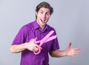 Man with huge scissors on gray background.