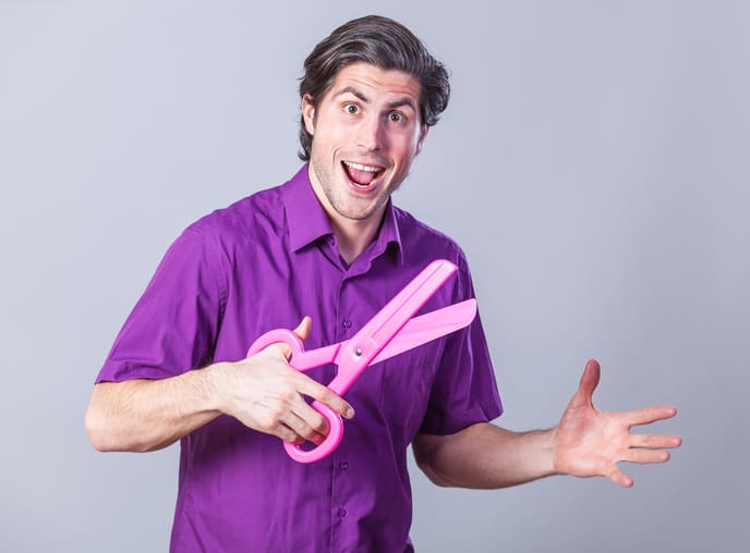 Man with huge scissors on gray background.
