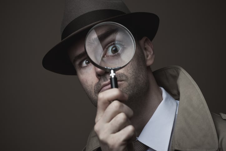 Vintage detective looking through a magnifier