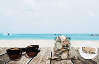 Saving money for vacation concept, glass coins container with sunglasses