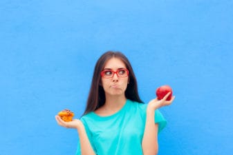 Woman Choosing Between Unhealthy Muffin and Healthy Apple
