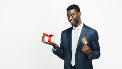 Smiling man holding beautiful gift and a golden credit card