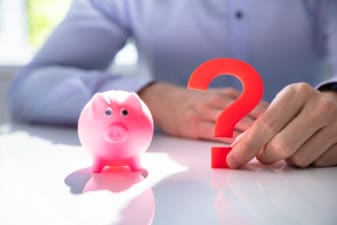 Man Holding Question Mark Next To Piggy Bank