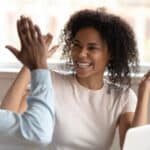 Young black colleagues high-fiving each other at work