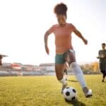 Young black female footballer training on stadium pitch