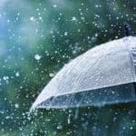 Transparent umbrella under heavy rain against water drops splash background.