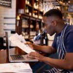 Business manager working at a pub doing the accountancy and some paperwork using a laptop computer
