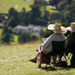 Two elderly people relaxing in the summer sunshine Box Hill near Dorking Surrey England