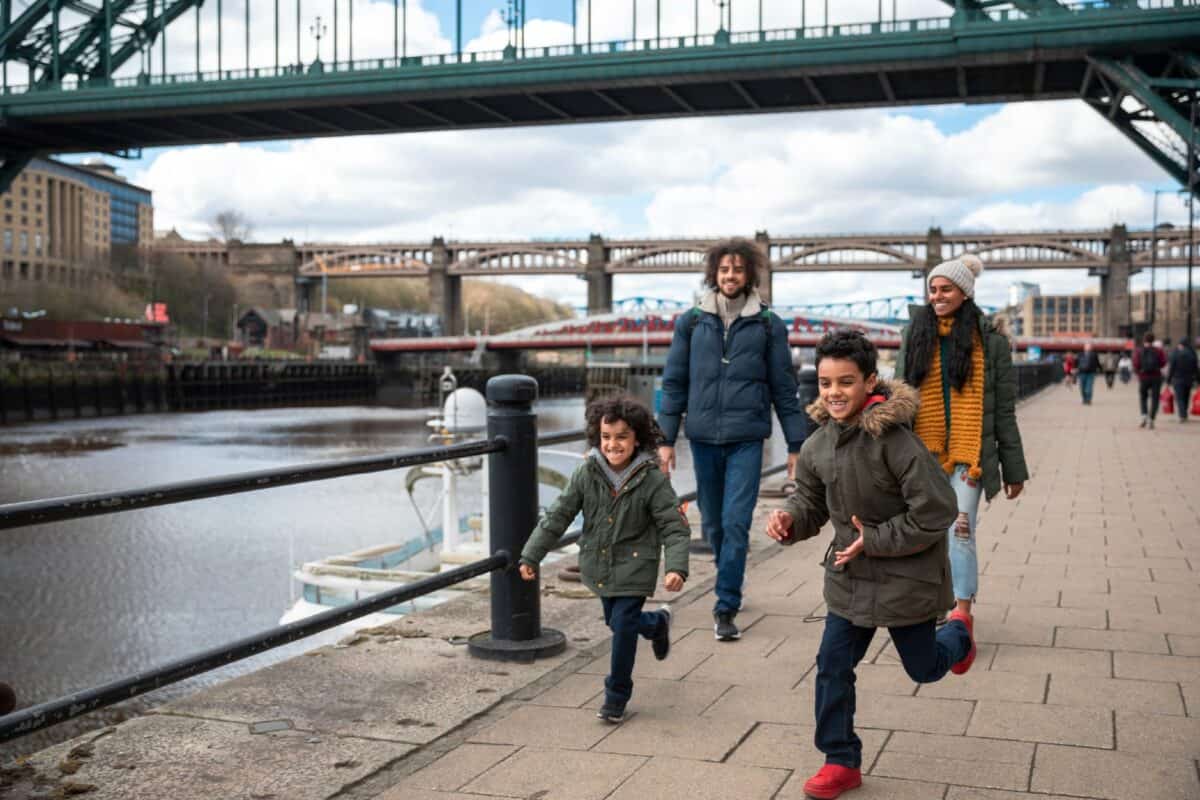 A multiracial family of four, a mother, father and their two little boys on a staycation in the city of Newcastle on a sunny winters day