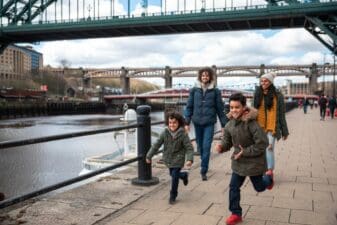 A multiracial family of four, a mother, father and their two little boys on a staycation in the city of Newcastle on a sunny winters day
