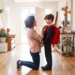 Mother At Home Getting Son Wearing Uniform Ready For First Day Of School