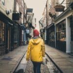 A rear view of a female in a bright yellow coat walking along the historic street known as The Shambles in York, UK which is a popular tourist destination in this Yorkshire city.