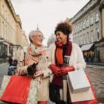Two female adult friends walking through the city streets at Christmas. They are talking and smiling as they do some Christmas shopping.