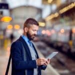 Businessman with tablet, waiting at the train station platform