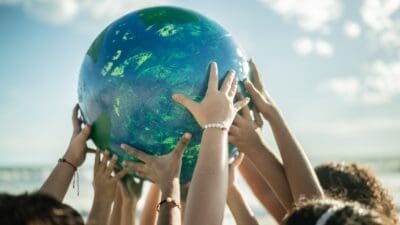 Close-up of children holding a planet at the beach