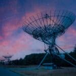 A row of satellite radars at night