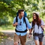 Happy couple hiking together in mountains with backpacks