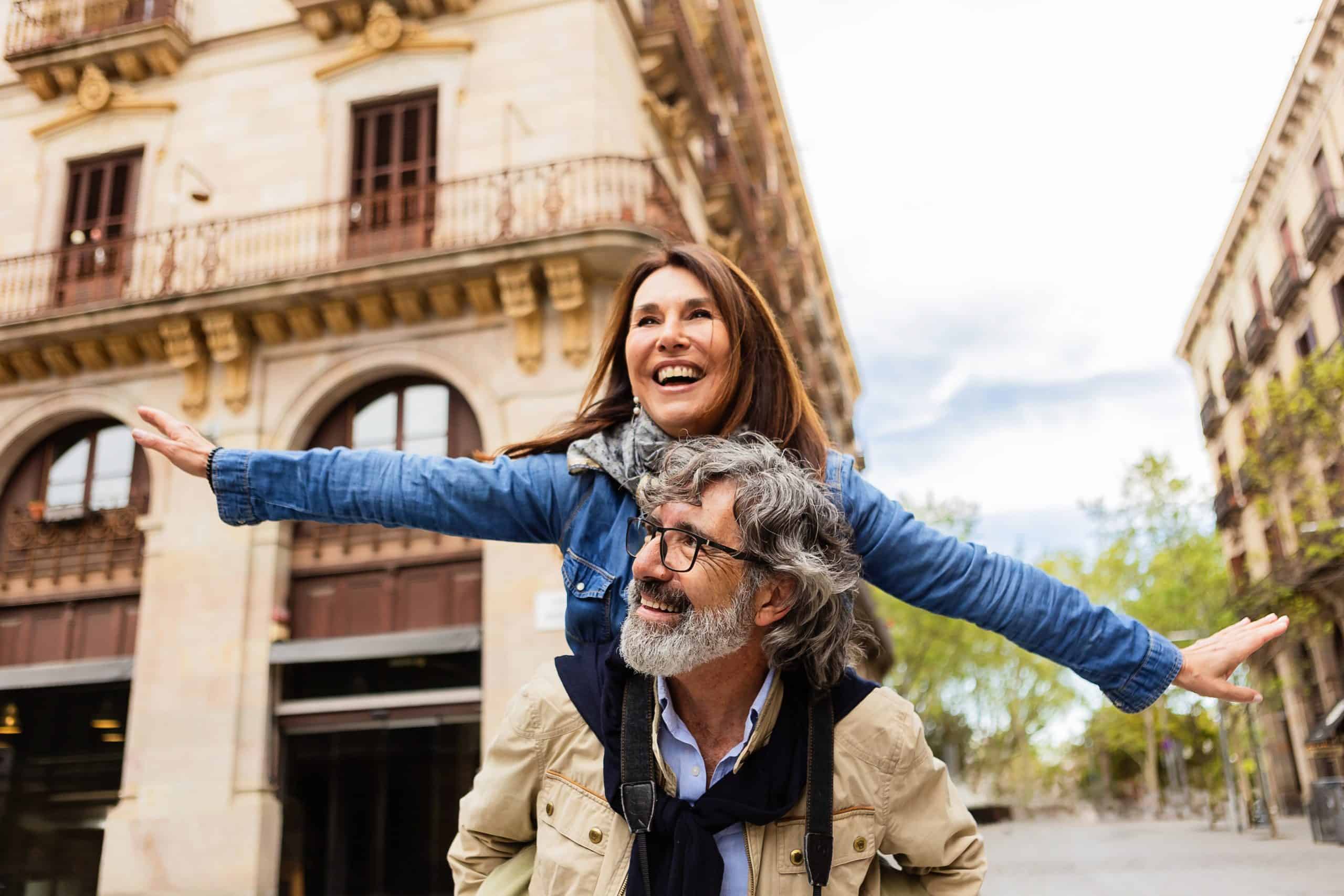 Joyful mature couple having fun together enjoying vacation on city street. Two retired older people enjoying time together during autumn holidays or weekend getaway