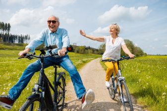Seniors having fun on bicycles in spring landscape